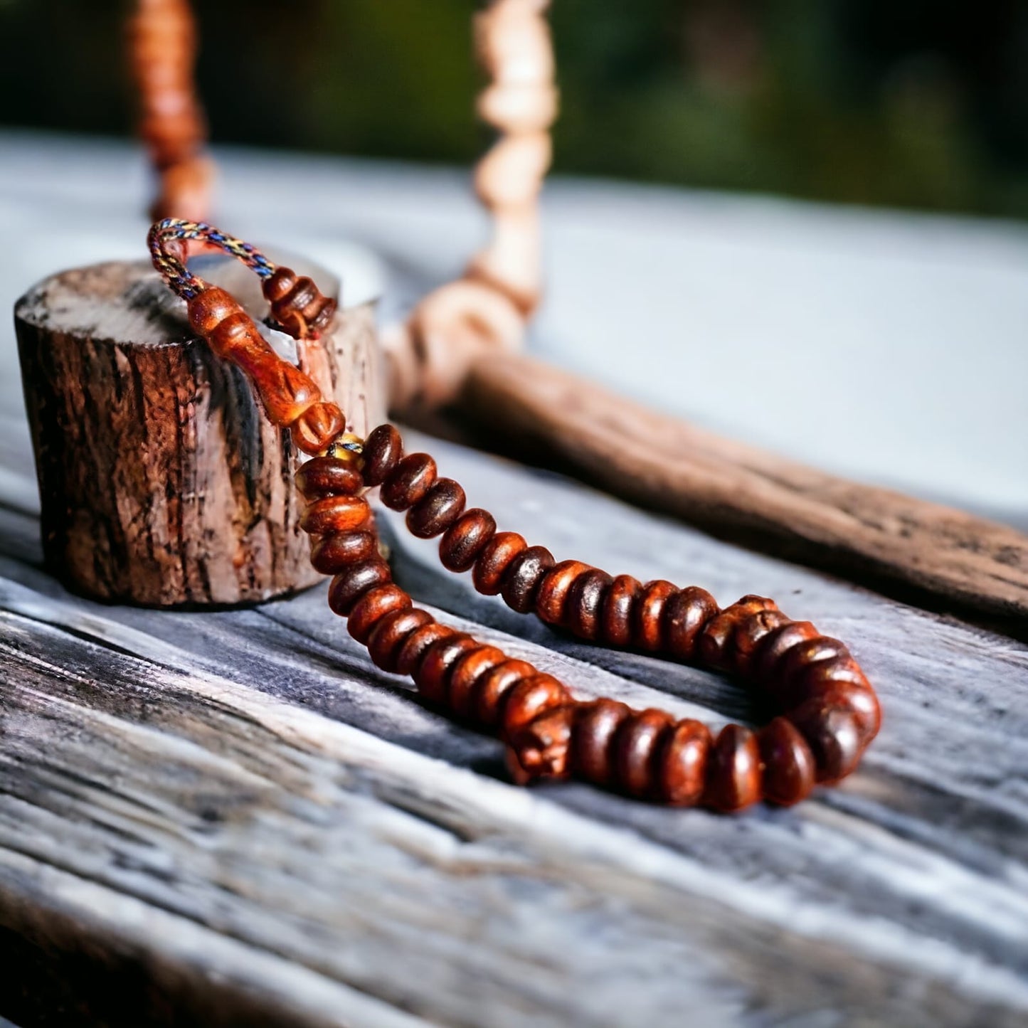 A close-up of Oud scented beads/Tasbeeh with wooden and amber colors, displayed on a wooden surface.